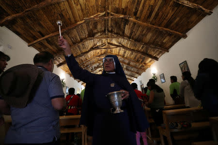 A nun sprinkles holy water on believers inside a church during a religious holiday in the Peine area on the Atacama salt flat in the Atacama desert, Chile, August 15, 2018. REUTERS/Ivan Alvarado