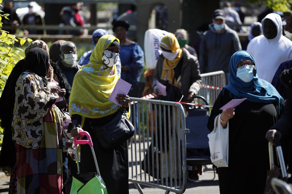 FILE - In this April 22, 2020, file photo, residents arrive to collect soap, vegetables, fruits and other staples distributed by volunteers from community organizations of ACLEFEU in Clichy-sous-Bois, a suburb north of Paris. Open-air markets are closed, supermarket prices are skyrocketing and people are out of jobs. Putting food on the table is yet another challenge for the disenfranchised residents of France’s housing projects, where the fallout of the national lockdown over the coronavirus is raising concerns about social unrest. (AP Photo/Francois Mori, File)