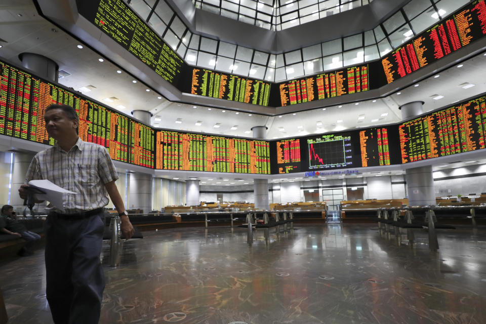 An investor walks in front of stock trading boards at a private stock market gallery in Kuala Lumpur, Malaysia, Thursday, July 18, 2019. Asian stock markets on Thursday followed Wall Street lower after President Donald Trump reignited trade fears by saying he could impose more tariffs on Chinese imports. (AP Photo/Vincent Thian)