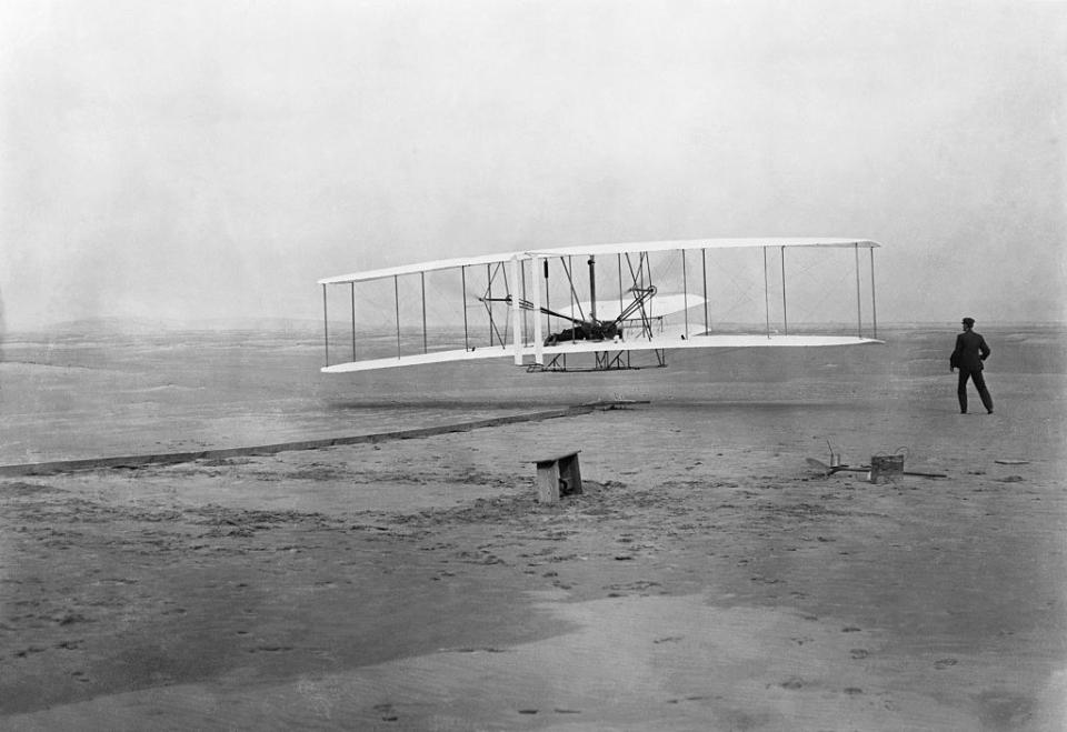 The Flyer takes off from Kill Devil Hill, with Orville Wright at the controls, while his brother Wilbur looks on, on December 17, 1903.