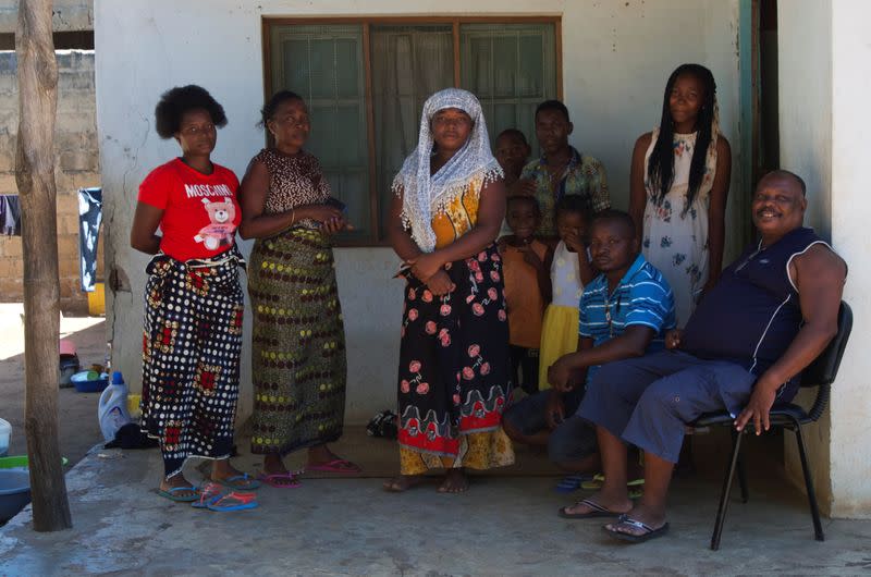 Peter N'Guila and his family sit with refugees who he is hosting after they fled an attack in Palma, at his home in Pemba