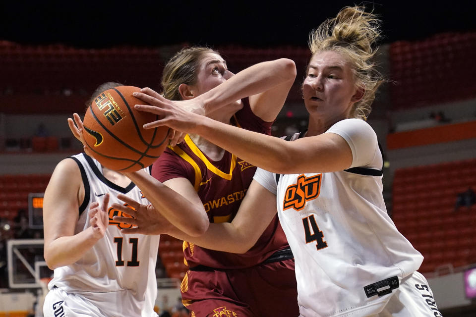 Oklahoma State guard Anna Gret Asi (4) knocks the ball away from Iowa State forward Morgan Kane, center, in the first half of an NCAA college basketball game, Wednesday, Feb. 22, 2023, in Stillwater, Okla. (AP Photo/Sue Ogrocki)