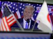 A TV screen showing U.S. President Donald Trump's speech is seen behind Japanese and U.S flags at a dealing room of the foreign exchange trading company Gaitame.com in Tokyo