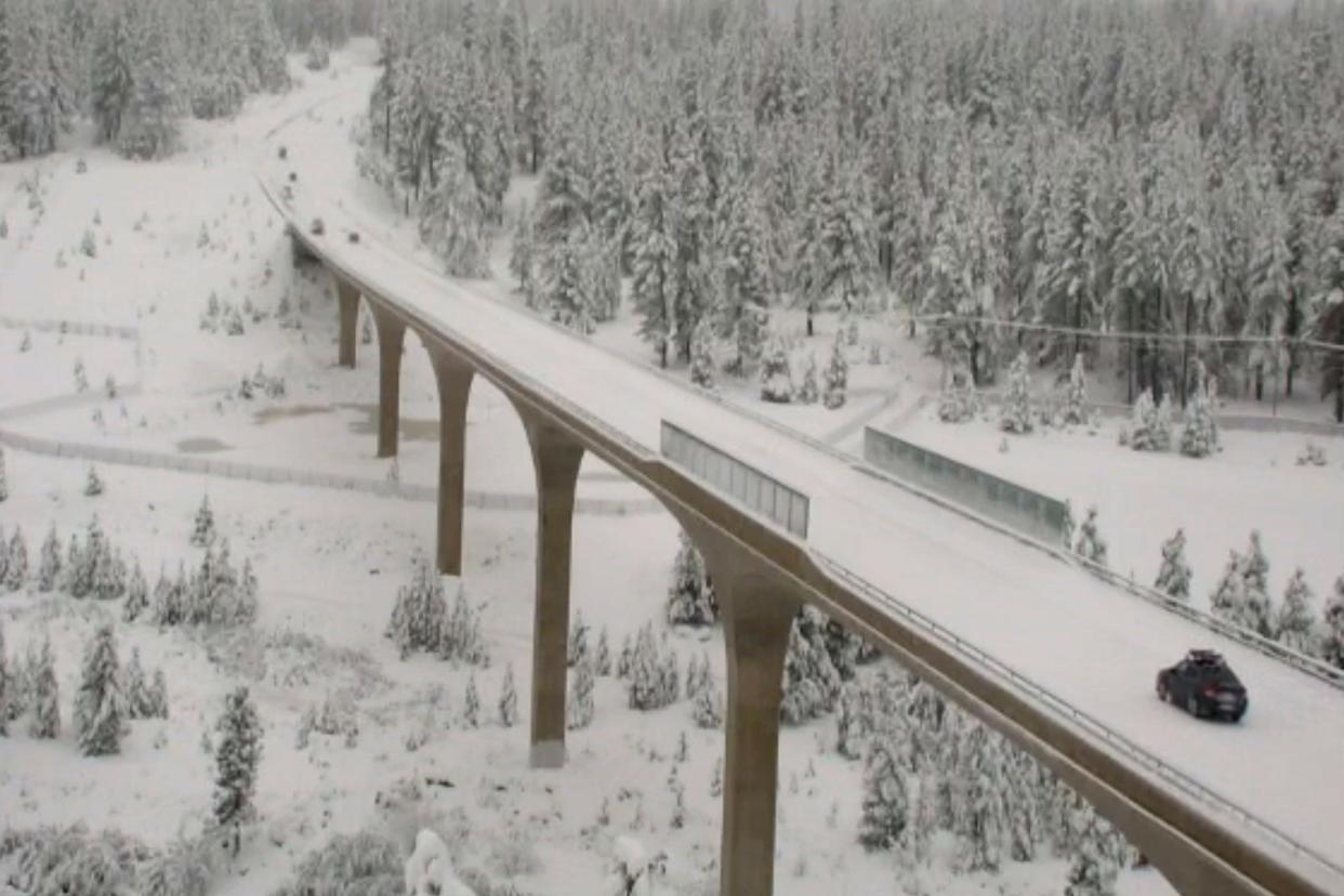 In this image taken from a Caltrans remote video traffic camera, light traffic is seen on the snow-covered Highway 267 bypass in Truckee, Calif., on Tuesday, Dec. 14, 2021. Motorists spun out on whitened mountain passes and residents wielded umbrellas that flopped in the face of fierce winds as Northern California absorbed even more rain and snow.