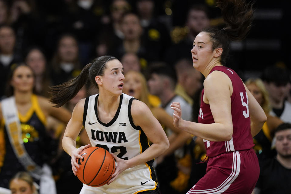 Iowa guard Caitlin Clark (22) drives around Indiana forward Mackenzie Holmes, right, during the first half of an NCAA college basketball game, Sunday, Feb. 26, 2023, in Iowa City, Iowa. (AP Photo/Charlie Neibergall)