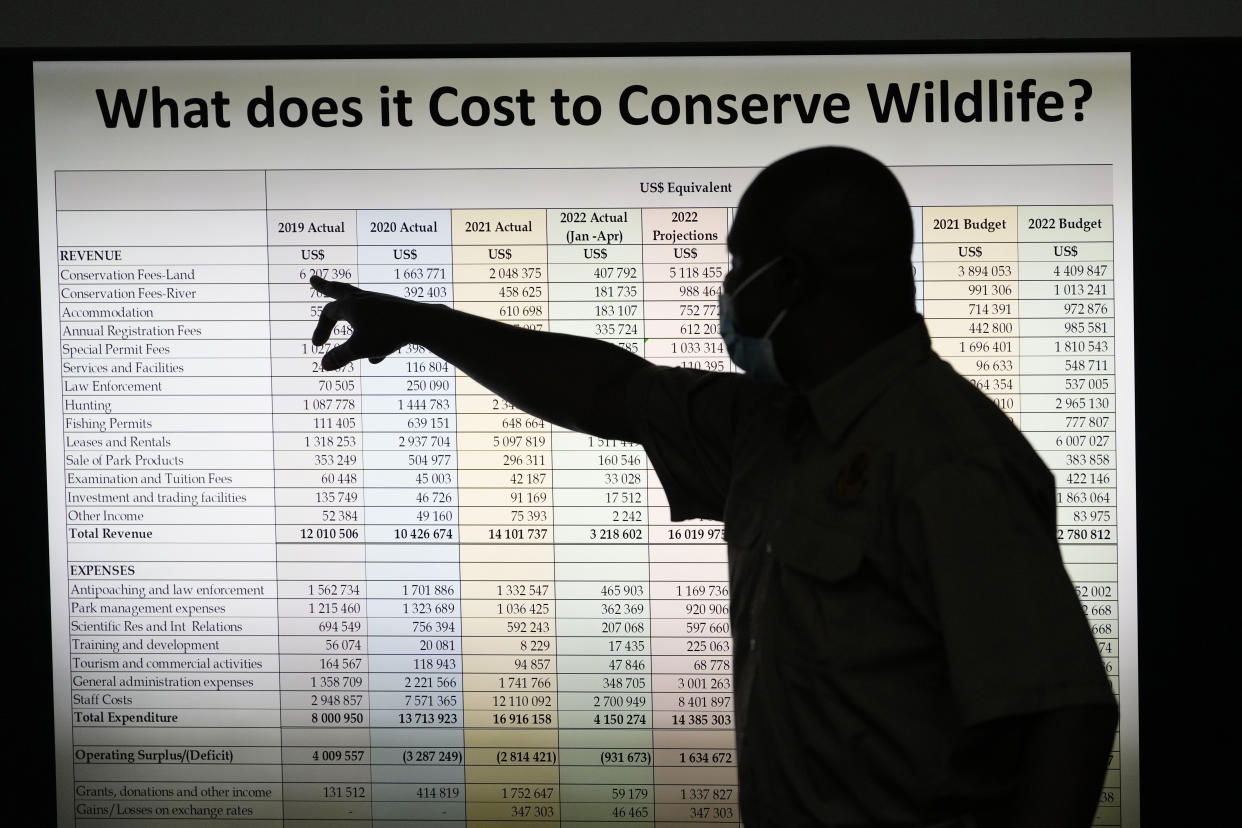A Zimbabwe National Parks official points to data during a presentation outlining the costs of conserving wildlife in the country during a tour of ivory stockpiles in Harare, Monday, May, 17, 2022. Zimbabwe is seeking international support to be allowed to sell half a billion dollars worth of ivory stockpile, describing the growth of its elephant population as “dangerous” amid dwindling resources for conservation. The Zimbabwe National Parks and Wildlife Management Authority on Monday took ambassadors from European Union countries through a tour of the stockpile to press for sales which are banned by CITES, the international body that monitors endangered species. (AP Photo/Tsvangirayi Mukwazhi)