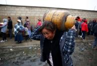 A woman carries a gas cylinder near petrol plant of Senkata, that normalizes fuel distribution in El Alto outskirts of La Paz