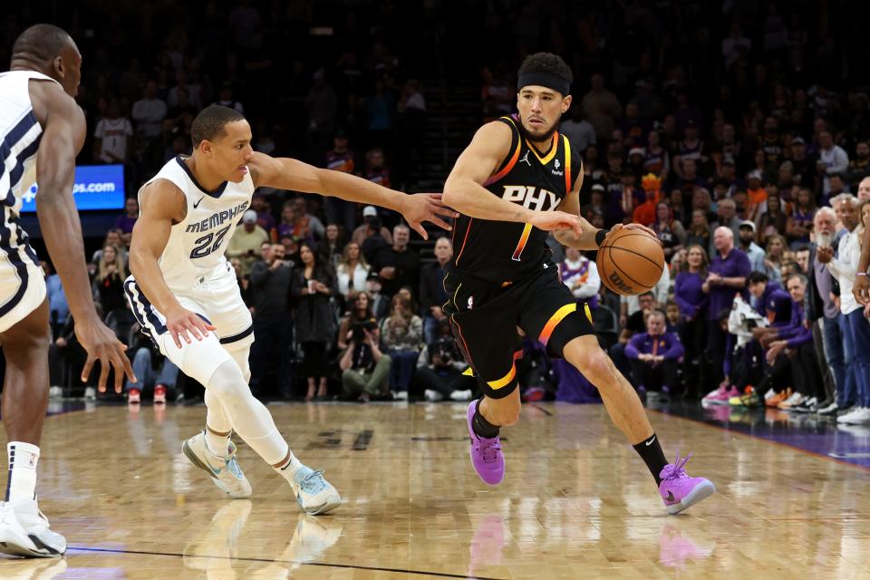 Devin Booker #1 of the Phoenix Suns drives to the net against Desmond Bane #22 of the Memphis Grizzlies at Footprint Center on Dec. 2, 2023, in Phoenix.