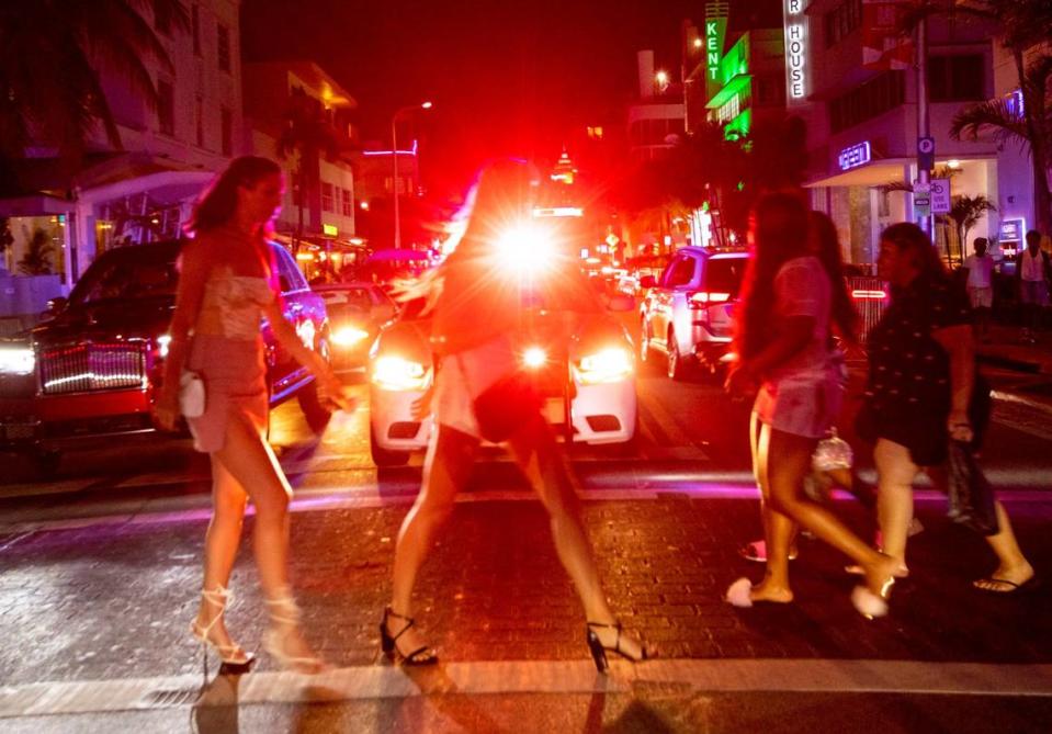 People cross Collins Avenue after curfew in Miami Beach, Florida, on Saturday, March 27, 2021.