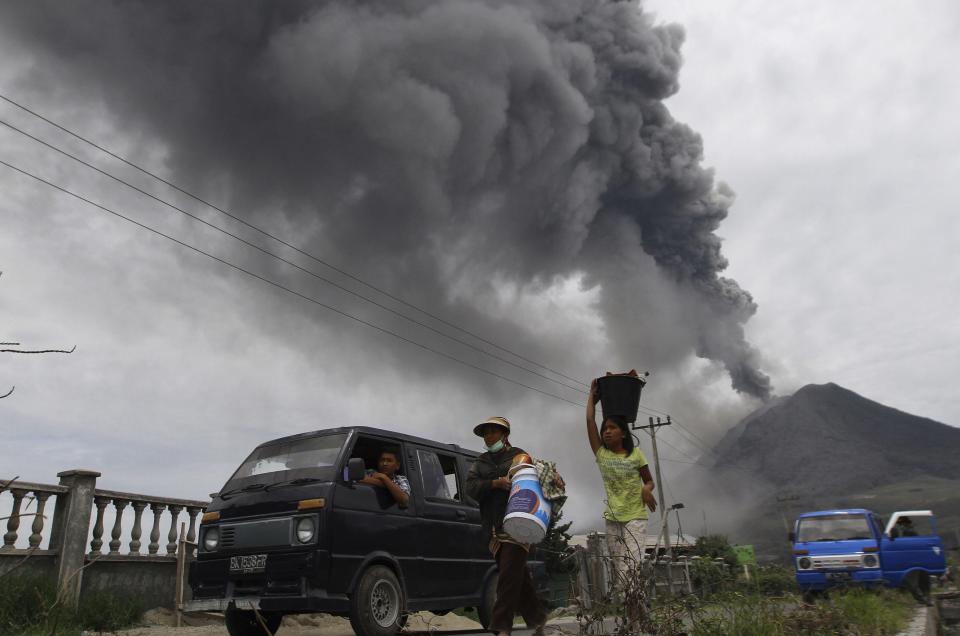 Villagers move to safety as Mount Sinabung spews ash and hot lava during an eruption in Perteguhan village