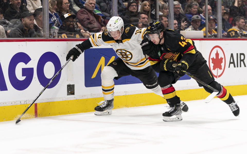 Vancouver Canucks' Quinn Hughes, right, and Boston Bruins' Trent Frederic get tangled up while chasing a loose puck during the second period of an NHL hockey game, Saturday, Feb. 25, 2023 in Vancouver, British Columbia. (Rich Lam/The Canadian Press via AP)