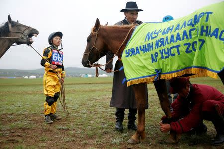 A horse trainer or uyach prepares for the send-off ceremony next to a jockey at the Mongolian traditional Naadam festival, on the outskirts of Ulaanbaatar, Mongolia July 11, 2018. Picture taken July 11, 2018. REUTERS/B. Rentsendorj