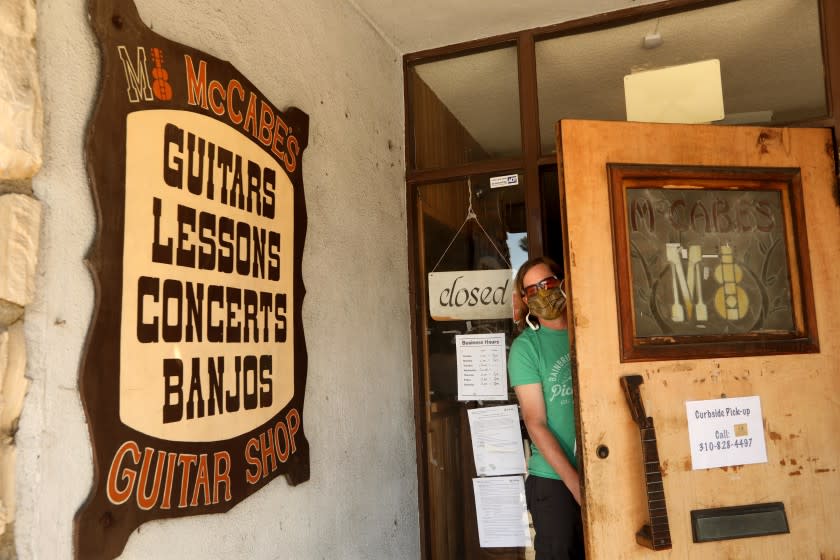 SANTA MONICA, CA - JUNE 7, 2020 - - Walt McGraw, looks out from the front door of McCabe's Guitar Shop in Santa Monica on June 7, 2020. After 50 years shop owners Bob and Espie Riskin are retiring due to fears from the coronavirus. The Riskin's daughter Nora McGraw and her husband Walt, pictured here, will manage the well known westside music venue. "No way are we going to let this place go down," said Walt McGraw. "This isn't just a music making business, it's a soul making business," he said. (Genaro Molina / Los Angeles Times)