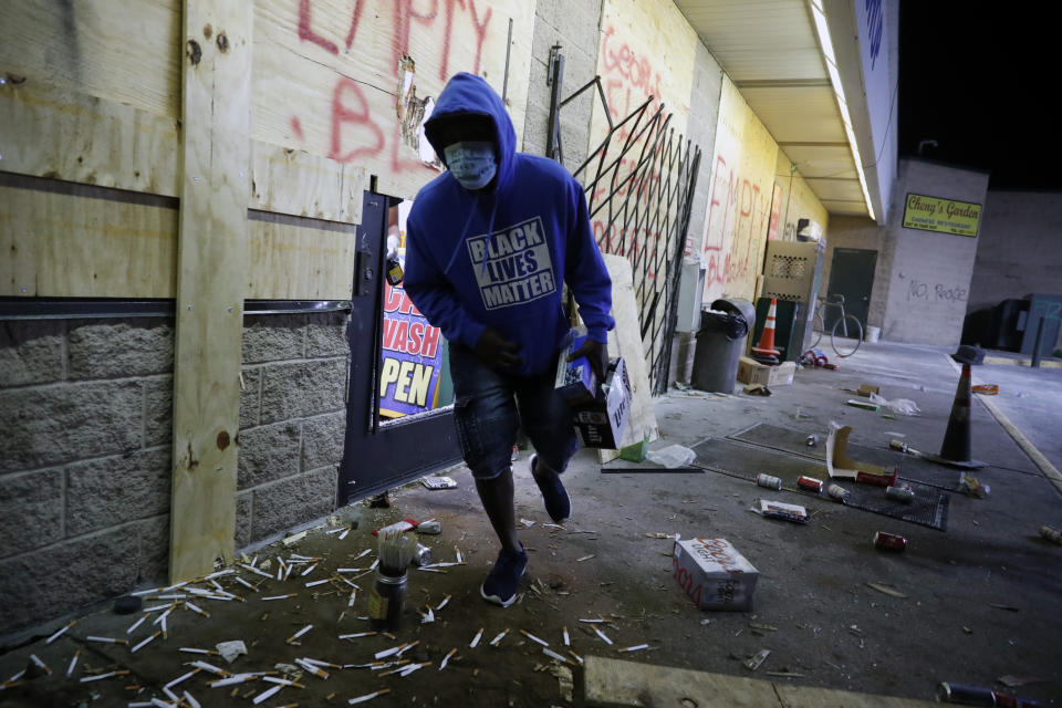 A man runs out of a convenience store Friday, May 29, 2020, in Minneapolis. Protests continued following the death of George Floyd, who died after being restrained by Minneapolis police officers on Memorial Day. (AP Photo/John Minchillo)