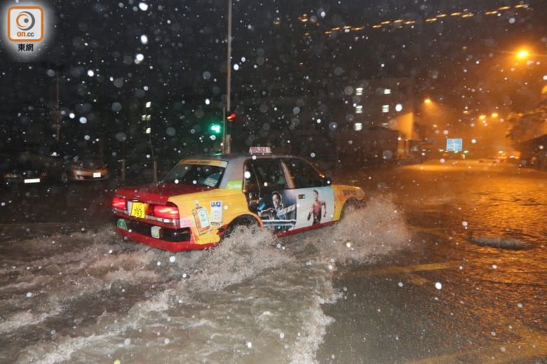 的士駛經水浸路面濺起水花。（李國健攝）