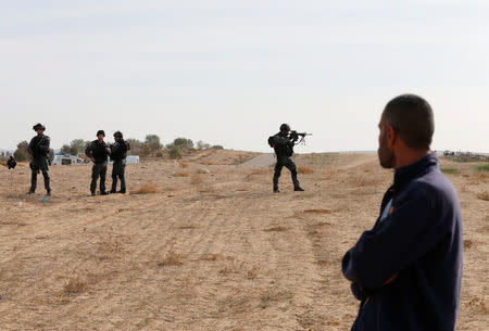 A Bedouin man looks at an Israeli border police holding his weapon as he patrols the area following clashes in Umm Al-Hiran, a Bedouin village in Israel's southern Negev Desert January 18, 2017. REUTERS/Ammar Awad