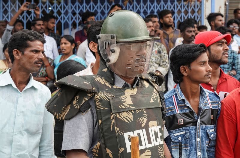 A police officer stands guard as people attend a protest against the alleged rape and murder of a 27-year-old woman in Shadnagar