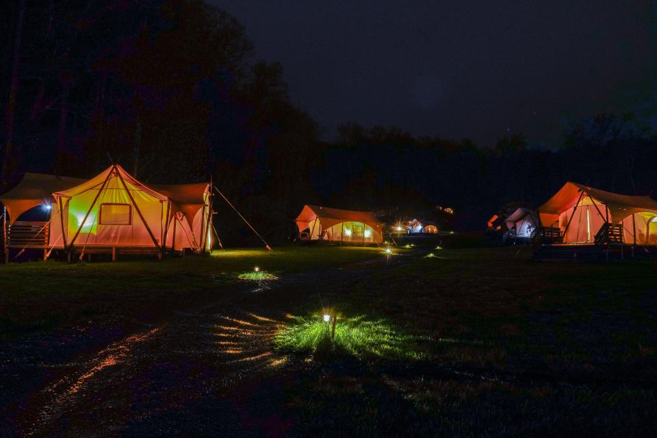 A night scene of glowing tents on a campsite.