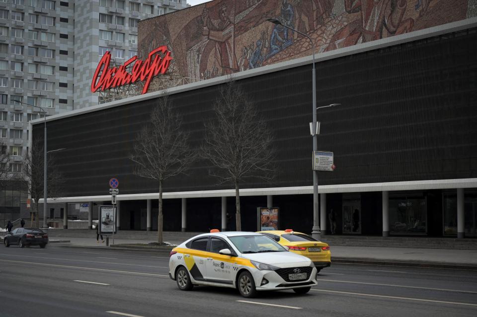 Cars are seen passing by the "Oktyabr" cinema in central Moscow.