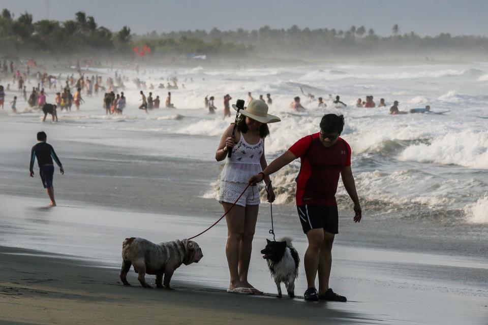 People walk their pet dogs during their summer vacation at a beach in Aurora Province, the Philippines, April 7, 2023. (Photo by Rouelle Umali/Xinhua via Getty Images)