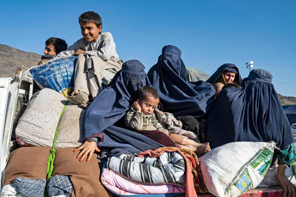 Afghan refugee Shazia (2R), mother to three children, holds an infant while travelling on a truck to Jalalabad from a makeshift camp (AFP via Getty)
