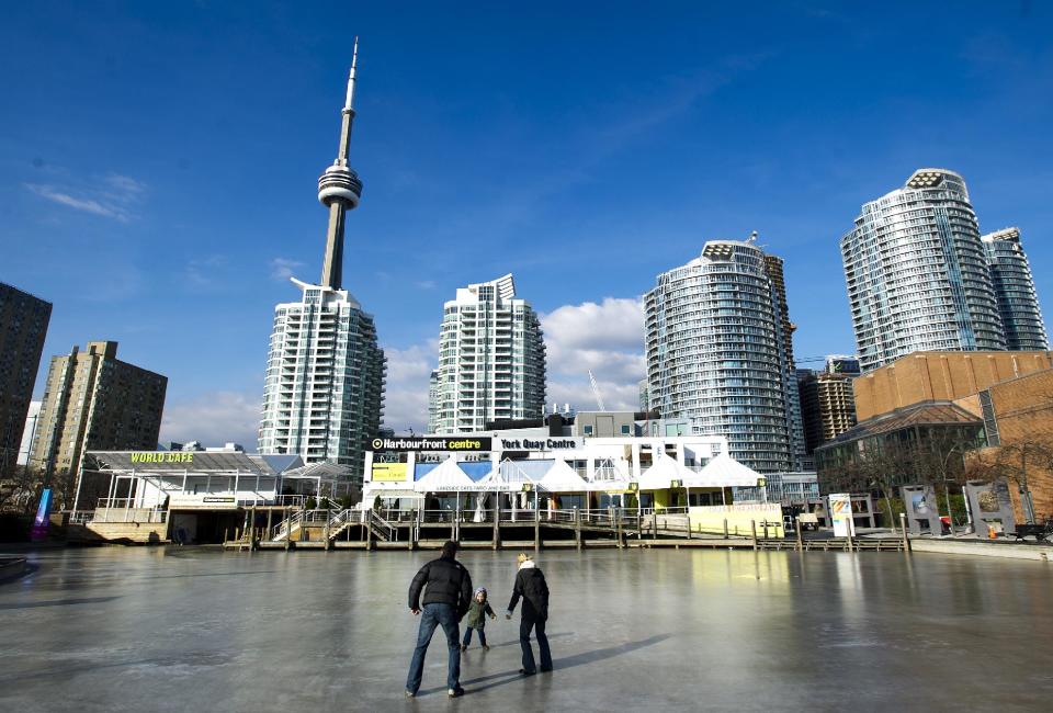 This Nov. 14, 2012 photo shows a family walking on ice near the board walk at Toronto's Harbour Front in Toronto. The Harbourfront Centre's 10-acre lakeside site hosts over 4,000 events, a large majority of which are gratis. The arts and culture hub's York Quay Center and The Power Plant have changing arts and photo exhibits year-round for no entry fee. (AP Photo/The Canadian Press, Nathan Denette)