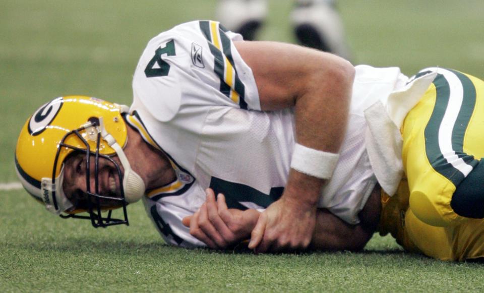 Green Bay Packers quarterback Brett Favre (4) grimaces as he holds his arm on the playing field against the Dallas Cowboys in the second quarter in their NFL football game, Thursday, Nov. 29, 2007, in Irving, Texas.