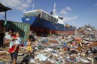 Residents walk past a cargo ship washed ashore four days after super typhoon Haiyan hit Anibong town, Tacloban city, central Philippines November 11, 2013.