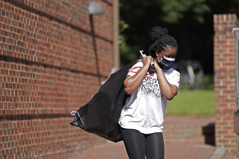 Oyeronke Popoola, a 17-year-old freshman from Raleigh, carries some of her belongings as she and other students leave campus following a cluster of COVID-19 cases at The University of North Carolina in Chapel Hill, N.C., Tuesday, Aug. 18, 2020. The university announced that it would cancel all in-person undergraduate learning starting on Wednesday. (AP Photo/Gerry Broome)