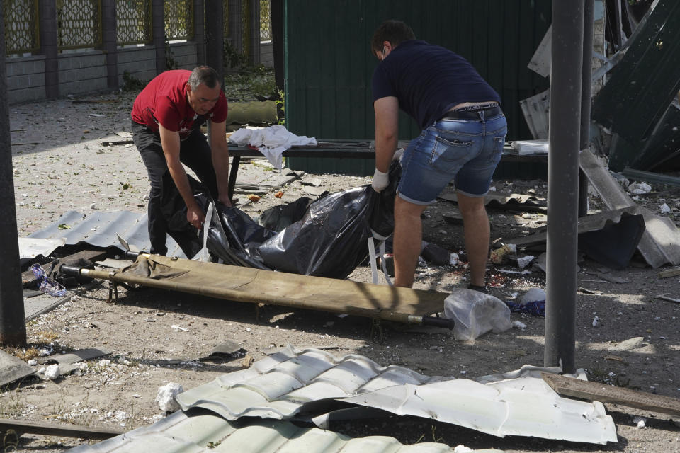 Men transfer the body of a victim killed by Russian shelling onto a stretcher in Kharkiv, Ukraine, Wednesday, July 20, 2022. (AP Photo/Andrii Marienko)