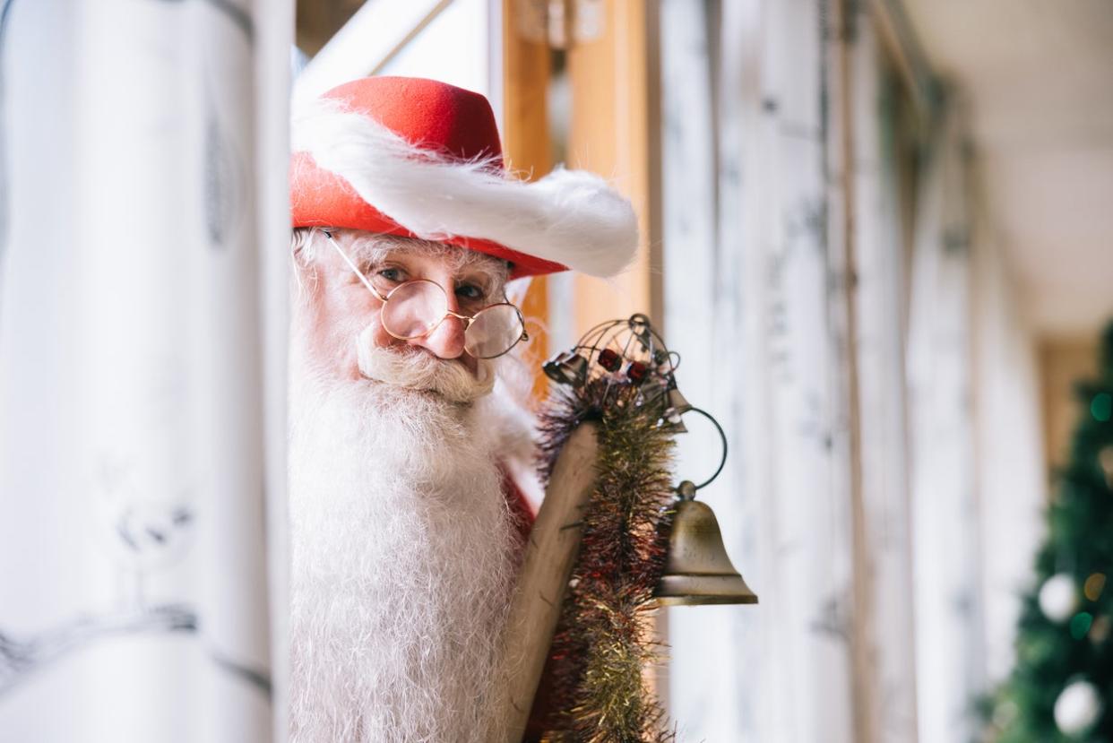 Santa-is-peeking-through-a-doorway-with-a-red-had-and-bells