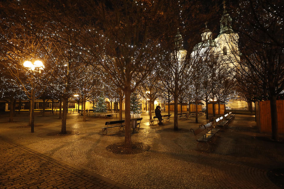 A security guard sits in the park near the Old Town Square in Prague, Czech Republic, Friday, Jan. 1, 2021. Due to the surge in coronavirus infections police boosted their presence across the country on New Year's Eve to enforce a night-time curfew starting at 9 p.m. and other strict restrictive measures imposed by the government that make it impossible to stage traditional New Year's celebrations. (AP Photo/Petr David Josek)