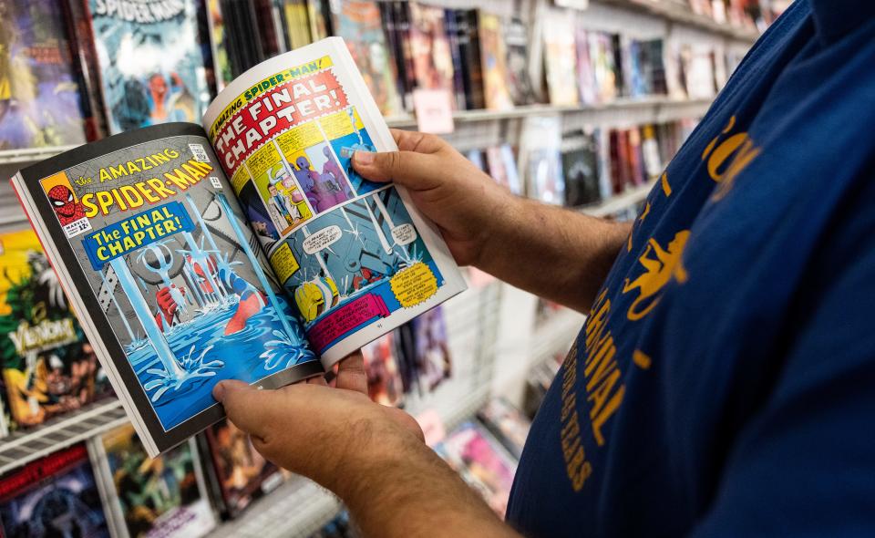 Tim Reynolds flips through a Spiderman comic Friday, Aug. 4, 2023, at Comic Carnival on North Keystone in Indianapolis. Started by Dan Gaines, Reynolds is now the owner of one of the oldest comic stores in the Midwest. Since 1975, Comic Carnival has been buying and selling comic books, statues, comic art, and more at his store.