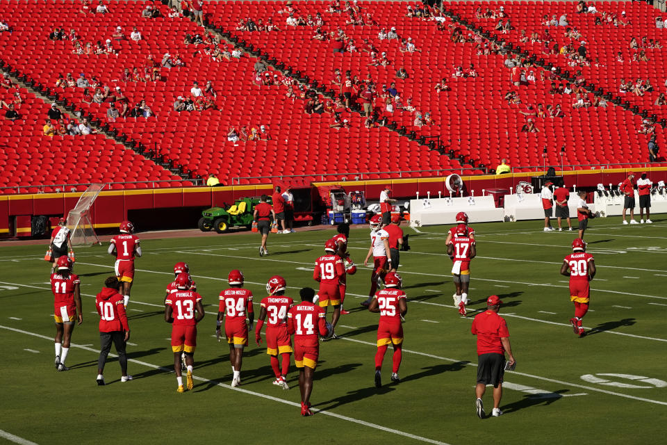 Arrowhead Stadium training camp showing players on the field and fans spread out in the stands.