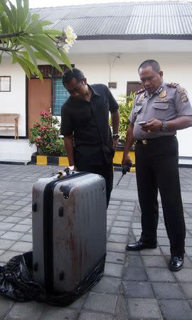 Police examine the suitcase in which the body of an American woman was found, at a police station in Nusa Dua, on the Indonesian holiday island of Bali August 12, 2014. REUTERS/Komang Ernii