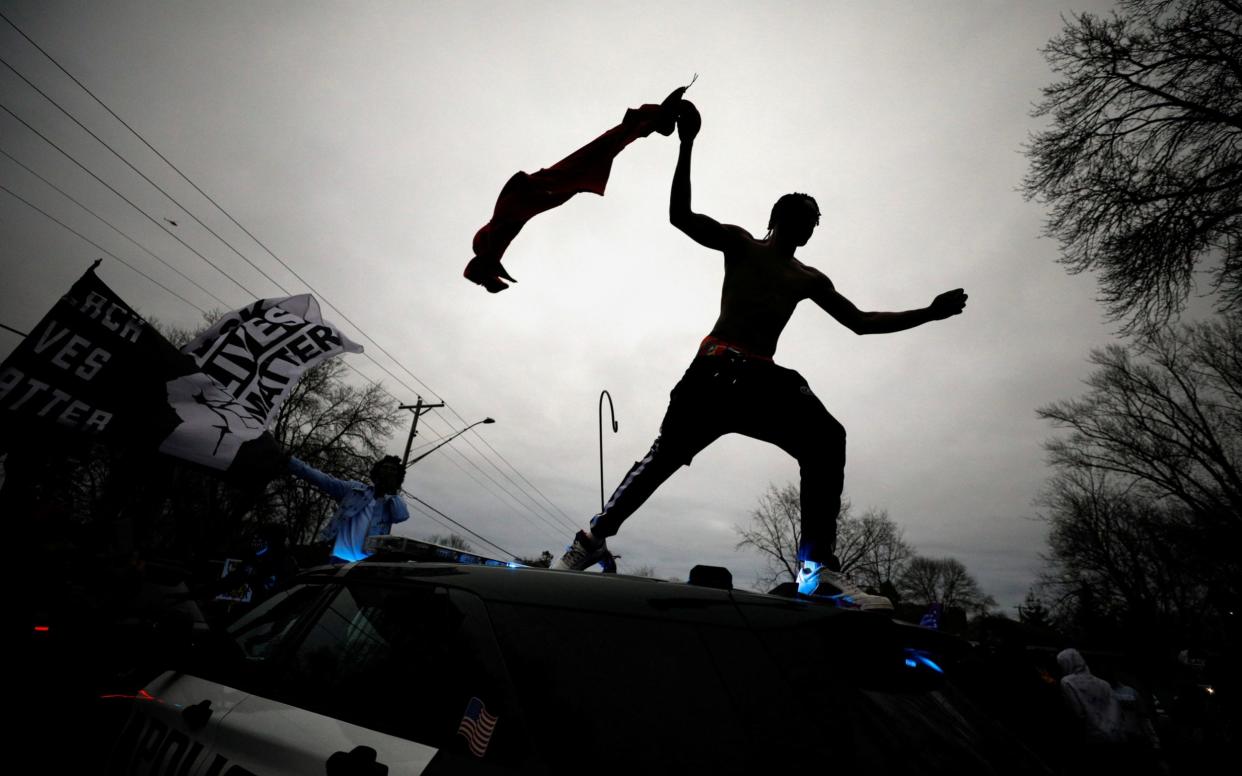 A demonstrator jumps off a police cruiser during a protest after police allegedly shot and killed Daunte Wright - NICHOLAS PFOSI /REUTERS