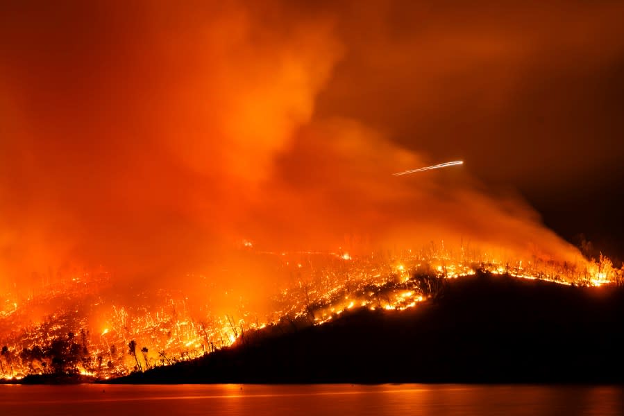 A helicopter flies over the Thompson Fire as it burns above Lake Oroville in Oroville, Calif., Tuesday, July 2, 2024. (AP Photo/Noah Berger)