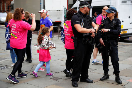 Armed police officers stand on duty as participants in a fun run walk past in central Manchester, Britain, May 28, 2017. REUTERS/Phil Noble