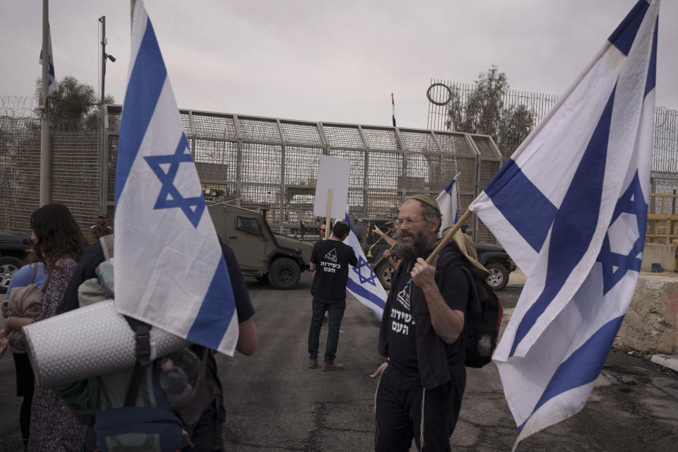 People stand in front of a gate at the Nitzana border crossing with Egypt in southern, Israel, Monday, Feb. 12, 2024, protesting against the humanitarian aid to enter Gaza until all the hostages are released. (AP Photo/Leo Correa)
