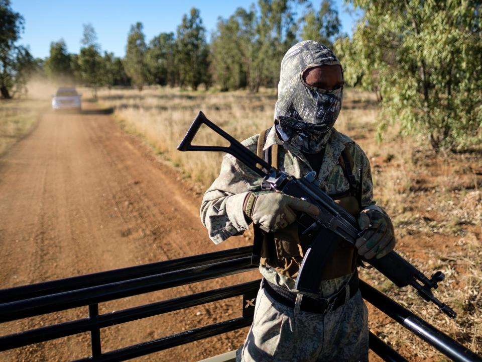 An armed guard rides in the back of a truck at the ranch of rhino breeder John Hume