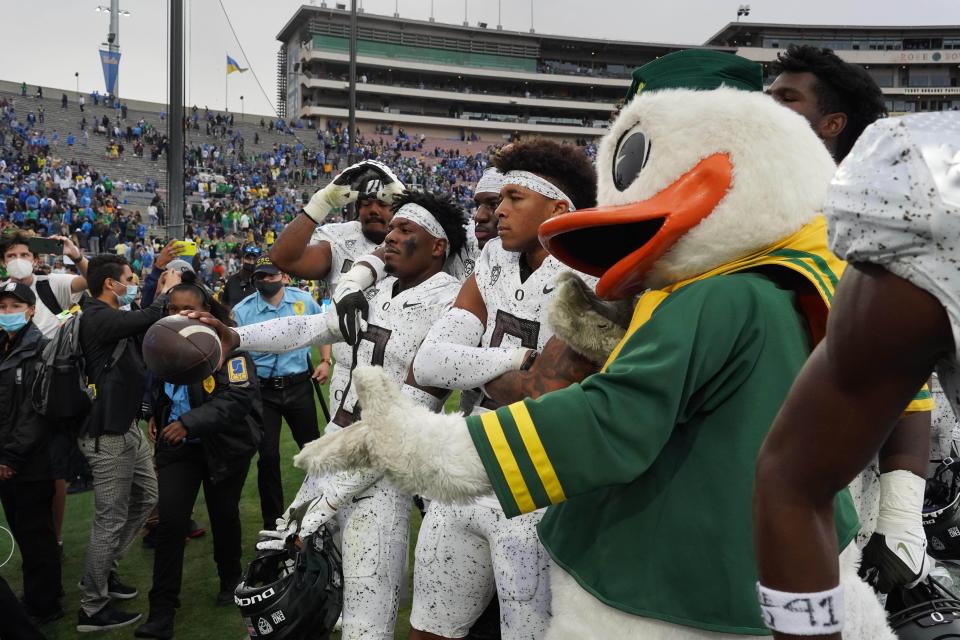 Oregon cornerback DJ James (0) poses with teammates and The Oregon Duck after the Ducks defeated UCLA.