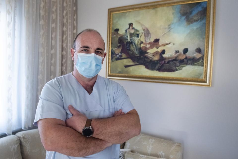 In this Saturday, Dec. 12, 2020 photo, Gabriel Tachtatzoglou poses at his house in Agios Athanassios, outside Thessaloniki city, northern Greece. Tachtatzoglou has worked as an ICU nurse in northern Greece for 20-years but when the pandemic struck his city in the fall, COVID-19 wards were quickly overwhelmed. He saw little choice other than to treat sick members of his family at home, setting up a treatment site with borrowed and rented medical machinery and using a hat stand to hold IV bags. (AP Photo/Giannis Papanikos)