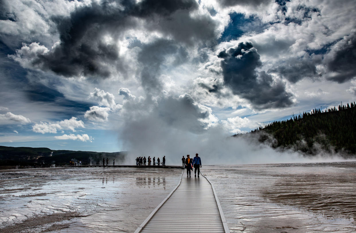 Visitors walk along a boardwalk at the iconic Grand Prismatic Spring in Yellowstone National Park. The geyser sits atop an active volcano caldera.