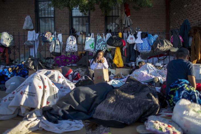 Venezuelan Genesis Rodriguez applies makeup after waking as people sleep around her outside a church.