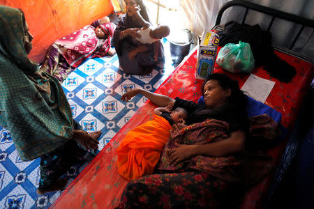 Monu Ara (R), a Rohingya refugee, lies on bed with her new born baby Belal Hussain while Tayeba Bugun lies on the floor as she waits to deliver at a medical center in Kutupalong refugees camp in Cox's Bazar, Bangladesh, October 14, 2017. Picture taken October 14, 2017. REUTERS/ Zohra Bensemra