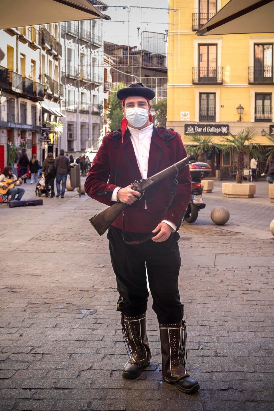 A man standing in the street holding a gun.