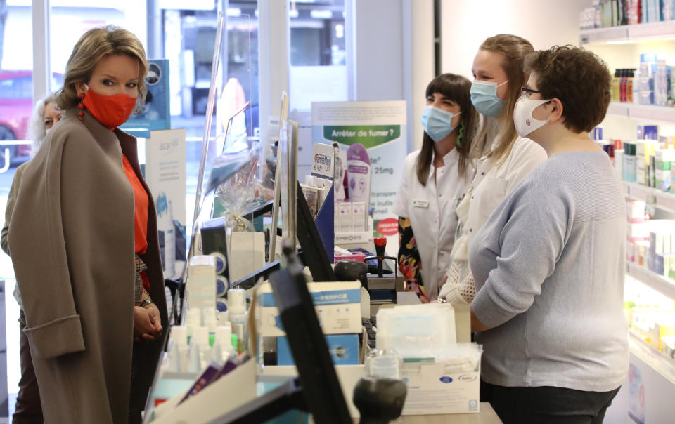 Belgium's Queen Mathilde, left, and pharmacy workers right, wear protective face masks to protect against the coronavirus, COVID-19, during an official visit to the Haelvoet Pharmacy in Brussels, Wednesday, Feb. 24, 2021. (Yves Herman, Pool via AP)