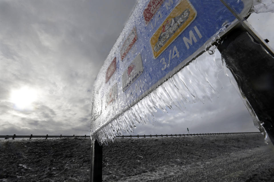 Icicles, formed by freezing rain and stiff winds, hang from a road sign along Interstate 84 as the sun tries to break through dark clouds in Troutdale, Ore., Wednesday, Jan. 18, 2017. An ice storm shut down parts of major highways and interstates Wednesday in Oregon and Washington state and paralyzed the hardest hit towns along the Columbia River Gorge with up to 2 inches of ice coating the ground in some places. (AP Photo/Don Ryan)