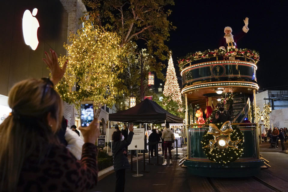 Santa Claus waves to shoppers from a safe distance at the top level of a trolly at The Grove shopping center in Los Angeles on Dec. 3, 2020. Santa visits were canceled due to the spread of COVID-19. In this socially distant holiday season, Santa Claus is still coming to towns (and shopping malls) across America but with a few 2020 rules in effect. (AP Photo/Ashley Landis)