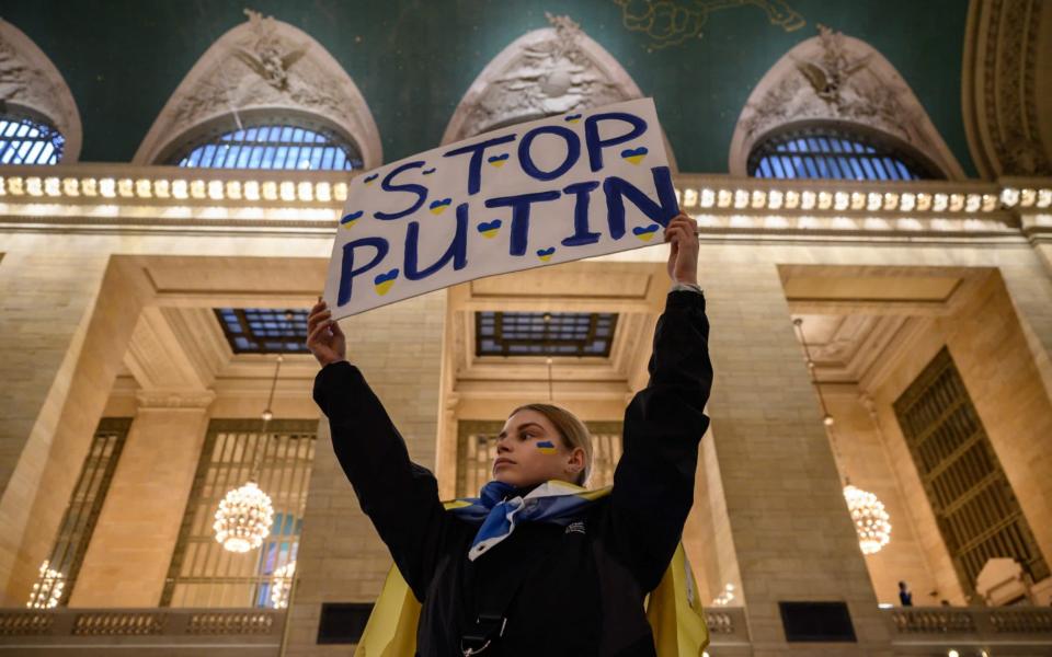 Activists hold placards during a protest in solidarity with Ukraine, at Grand Central Station in New York - AFP